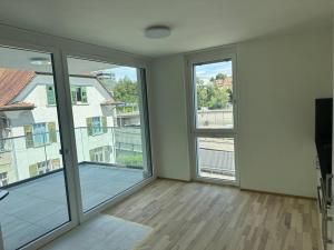 an empty living room with large windows and a balcony at Wohnung Neubau in Schaffhausen in Schaffhausen