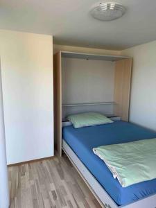 um quarto com uma cama com lençóis azuis e uma parede em Wohnung Neubau in Schaffhausen em Schaffhausen