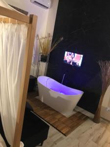 a bathroom with a tub with a tv on the wall at Villa White Luxury Residence in Marsala