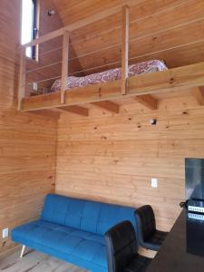 Cette chambre dispose d'un canapé bleu et de lits superposés. dans l'établissement Cabaña nórdica en la naturaleza, à Punta Ballena