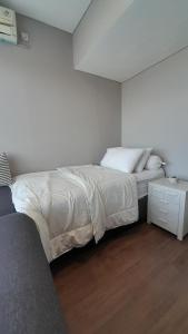 a white bedroom with a bed and a night stand at Ruby Apartment #23 in Yogyakarta +3 photos