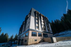 a building in the snow with a blue sky at Lux apartment Zlatni Javor Jahorina in Jahorina