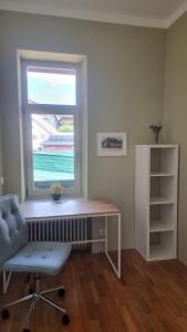 einen Schreibtisch und einen Stuhl in einem Zimmer mit Fenster in der Unterkunft Schöne einfache Wohnung in Jugendstilhaus in Feistritz an der Drau