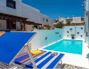 a swimming pool with two chairs next to a house at Villa Arcelia in Puerto del Carmen
