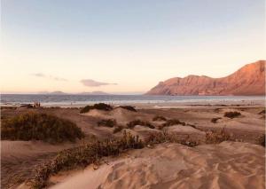 una spiaggia sabbiosa con vista sull'oceano e sulle montagne di Talia II apartement a Teguise