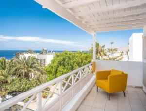 a balcony with a yellow chair and the ocean at Villa Arcelia in Puerto del Carmen