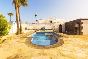 a pool with a bench in a yard with palm trees at Luxury Villa Alfred in Puerto del Carmen