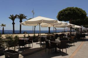 a restaurant with tables and umbrellas on the beach at Dúplex Vista Mar Puerto Del Carmen in Puerto del Carmen