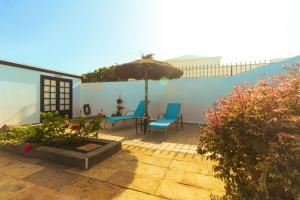 a patio with two chairs and an umbrella at Luxury Villa Alfred in Puerto del Carmen