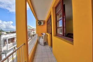 a balcony with a yellow wall and a window at Appartement tout confort in Sainte-Anne