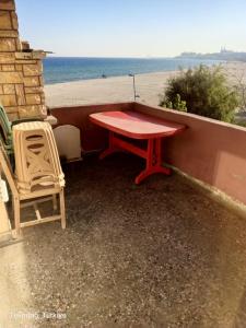 a red table and a chair sitting on a ledge next to the beach at Sultanköy Apart in Marmaraereglisi