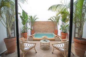 a patio with a pool and chairs and plants at Riad Coconut in Marrakech