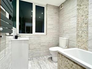 a bathroom with a toilet and a tub and a sink at Perfect Stay For Family & Contractors With Free Parking in Luton