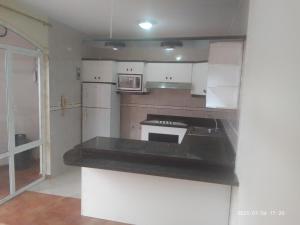 uma cozinha com armários brancos e um balcão preto em Apartamento en Vilcabamba em Vilcabamba