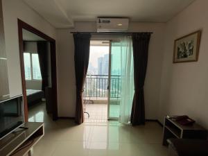 a living room with a door open to a balcony at Comfy 1BR At Central ( City View ) in Jakarta