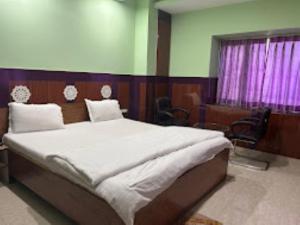 1 dormitorio con 1 cama grande con sábanas blancas en Hotel 707 Bhubaneswar, en Bhubaneshwar