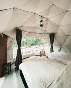 a bedroom with a tent with a bed and a window at Nomad inn Tiwi in Ḩillat al Ḩişn