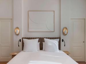 um quarto com uma cama branca e 2 almofadas brancas em Elkonin Tel Aviv - MGallery Hotel Collection em Tel Aviv