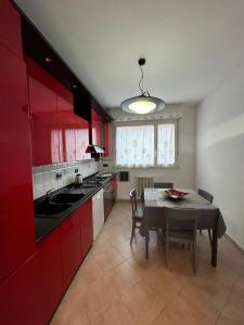 kuchnia z czerwonymi szafkami i stołem z krzesłami w obiekcie Cà Savoia w Bolonii