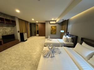 a hotel room with two beds and a flat screen tv at Premier Hostel Chiang Mai in Chiang Mai