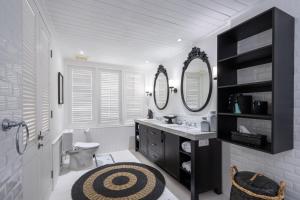 a bathroom with a sink and a toilet and two mirrors at White Horse Resort in Nusa Lembongan