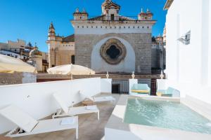 a patio with chairs and a swimming pool in front of a building at Ninesuites Cathedral in Seville