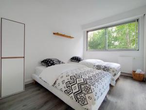two beds in a white room with a window at Chic and comfortable apart near Paris in Colombes
