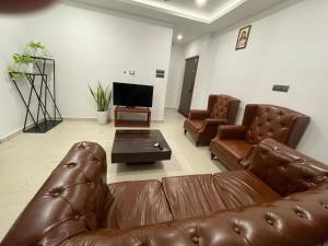 a living room with a leather couch and a television at BMRAN Luxury serviced apartment in Cochin
