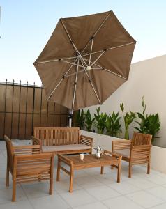 three chairs and a table with a large umbrella at 2 Bedroom Apartment in Jeddah in Jeddah