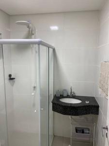 uma casa de banho branca com um lavatório e um chuveiro em Loft veraneio em Balneário Camboriú