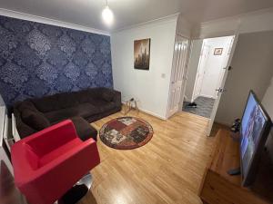 uma sala de estar com um sofá e uma cadeira vermelha em Mannys Apartment - Nice & Cozy 4Bed Flagship Lodge em Sittingbourne