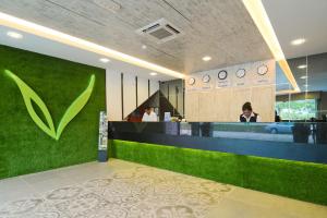 a lobby with a green wall and a woman at a counter at De Parkview Hotel in Ipoh