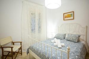 a white bedroom with a bed and a chair at WISH SUITE CALATRAVA DE SEVILLA in Seville