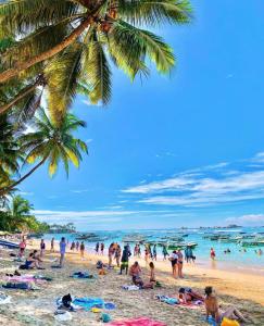 un gruppo di persone su una spiaggia con una palma di RM Holiday Home a Hikkaduwa
