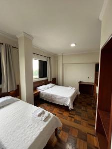 um quarto de hotel com duas camas e uma janela em Acomodare Hotel em Tubarão