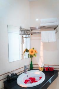 um lavatório de casa de banho com um vaso de flores em Victoria Hotel Me Tri em Hanói