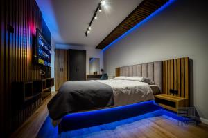 1 dormitorio con 1 cama grande y una iluminación azul en Elite Studio Apartament, en Câmpulung Moldovenesc
