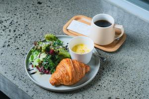 um prato de comida com um croissant e uma chávena de café em Of Hotel em Sendai