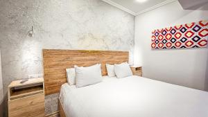 a bedroom with a white bed with a wooden headboard at Hotel Bankir Khiva in Khiva