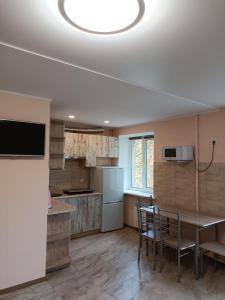 a kitchen with a dining table and a kitchen with a refrigerator at Апартаменти центр біля озера in Ternopilʼ