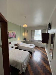 a hotel room with two beds and a television at Oscar Palace Hotel - Centro de Tubarão in Tubarão
