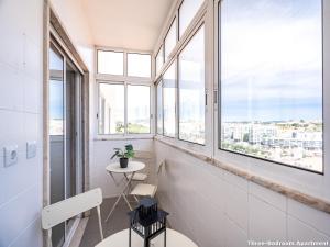 Zimmer mit Fenstern, einem Tisch und einem Stuhl in der Unterkunft Akicity Ameixoeira Light in Lissabon