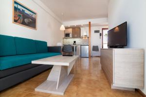 a living room with a blue couch and a tv at Apartamentos Montemayor in Playa del Ingles