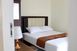 a bed with white sheets and a brown blanket at Bungo Bed & Breakfast Workation in Bukittinggi