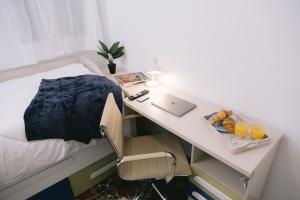 a bedroom with a bed and a desk with a laptop at Piso compartido Delyrent, Reja in Jaén