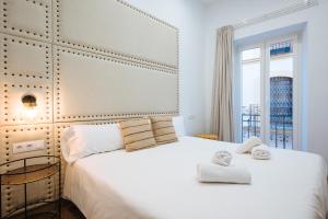 um quarto com uma grande cama branca com toalhas em Ninesuites Cathedral em Sevilha