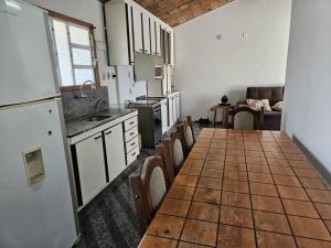 una cocina con una mesa larga con sillas. en Casa a 600m praia dos Ingleses en Florianópolis