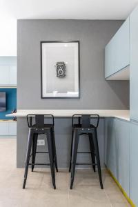a kitchen with two stools at a counter with a picture at Estudio moderno y acogedor en Madrid Rio nº5 in Madrid