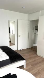 a white bedroom with a bed and a mirror at LouVi in Kehl am Rhein