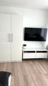 a living room with a television and white cabinets at LouVi in Kehl am Rhein